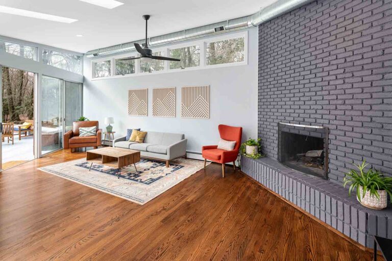 Modern living room with orange chairs and purple fireplace bricks